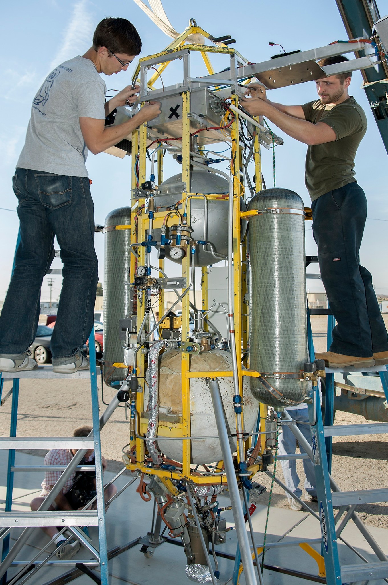 two researchers stand on ladders to work on Xombie