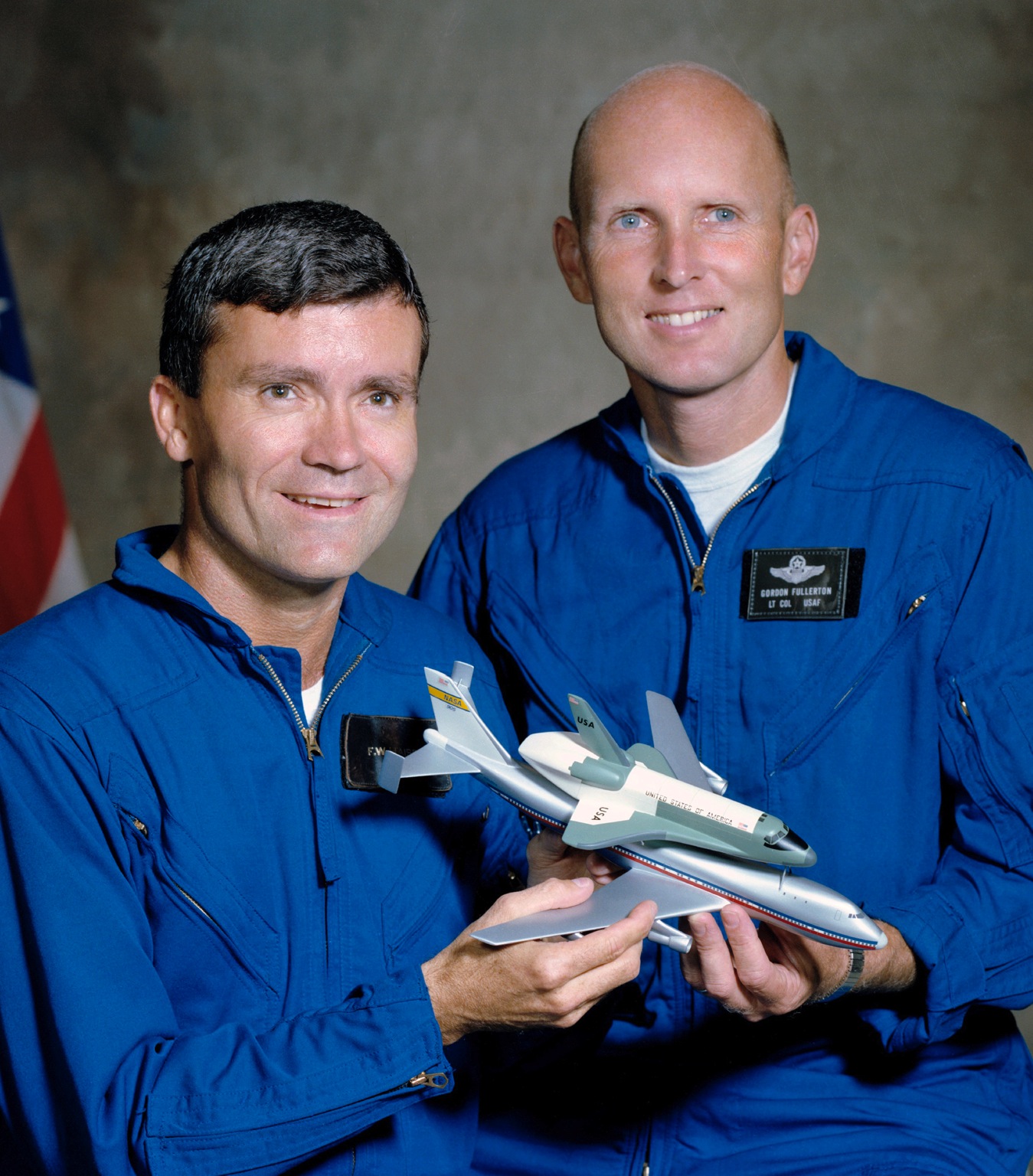 Portrait of Fred Haise and Gordon Fullerton holding a model of the Space Shuttle mated to the Shuttle Carrier Aircraft