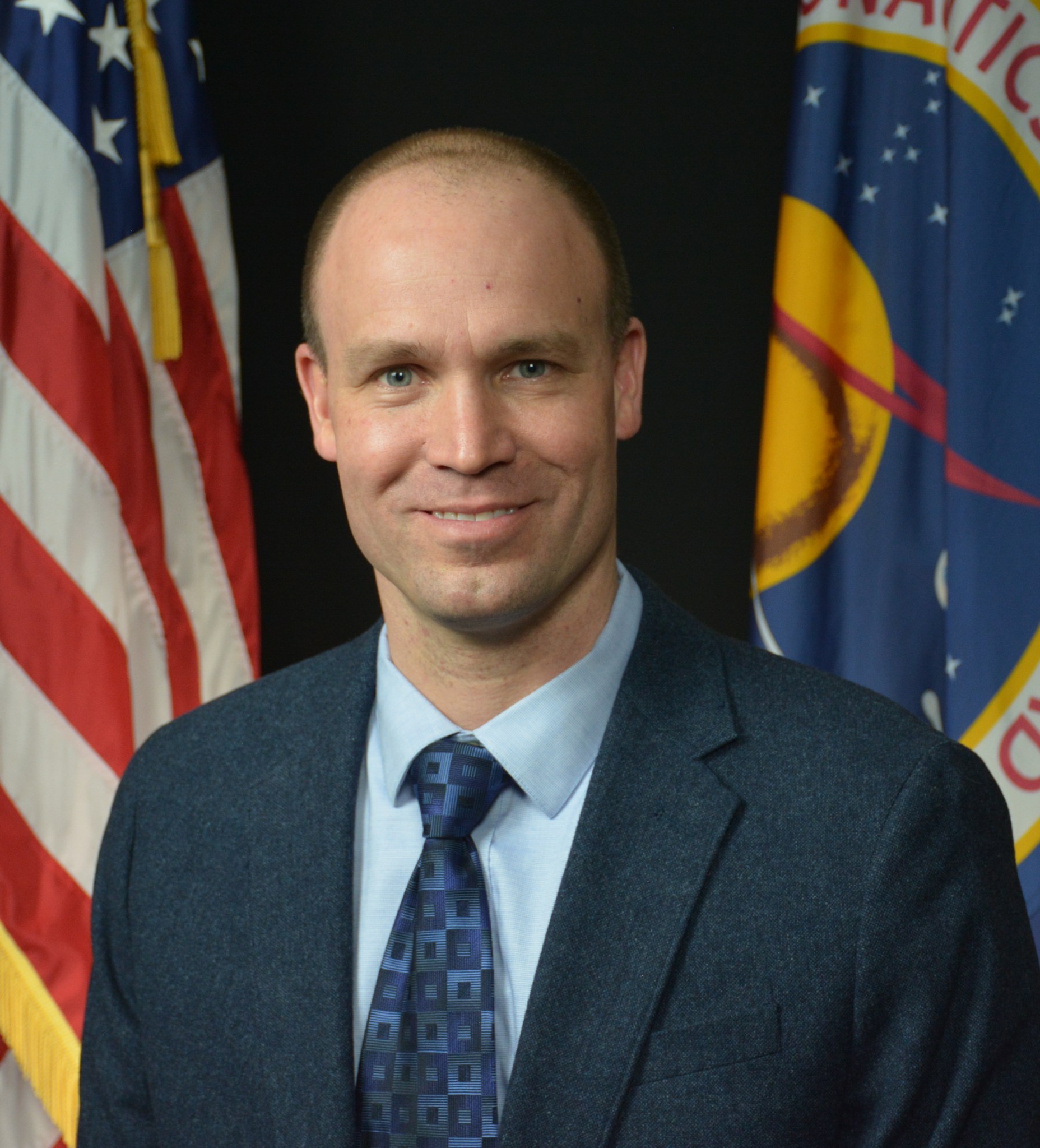 A man smiling sitting between two flags