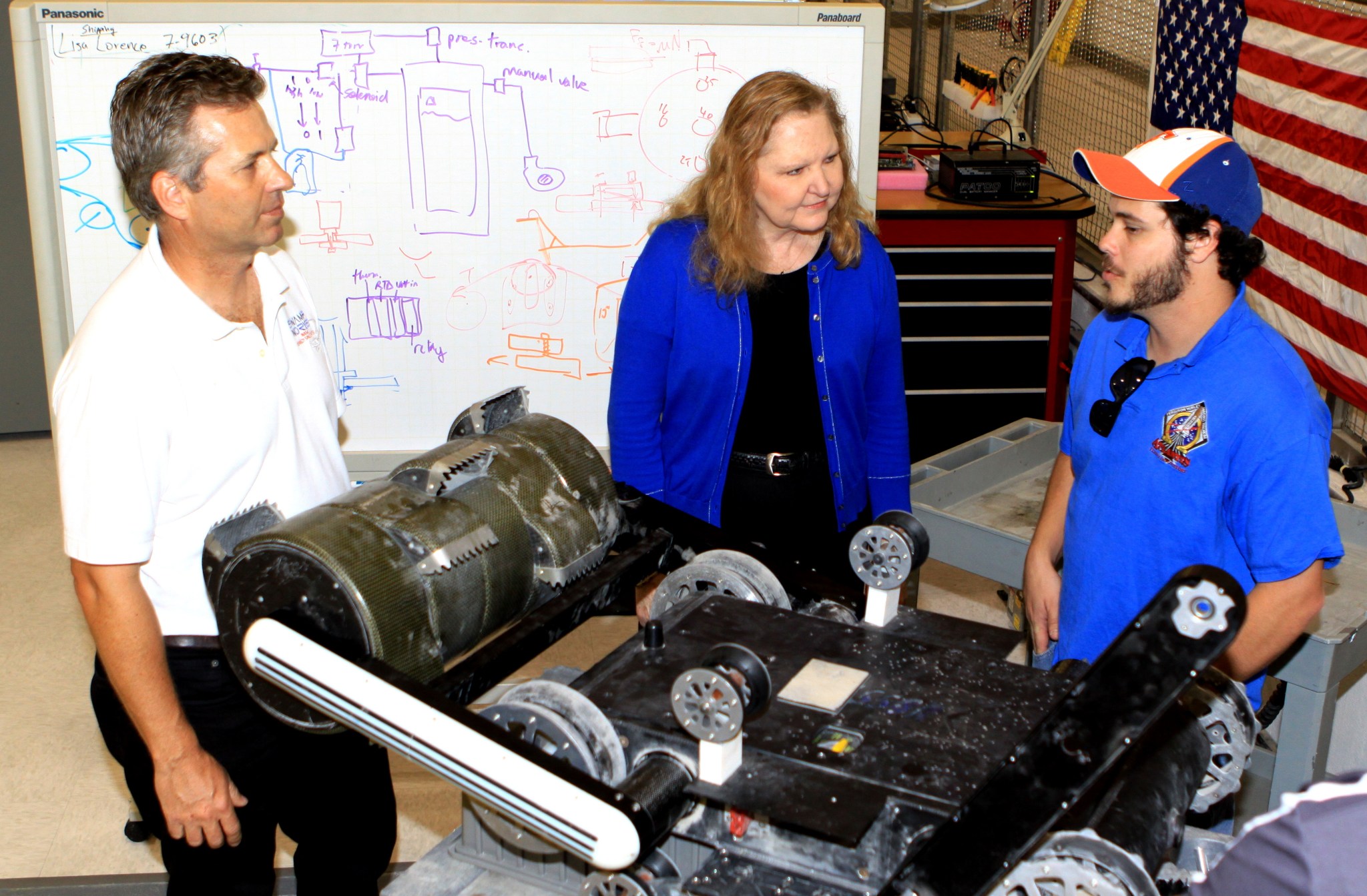 NASA technology experts at the Kennedy Space Center examine a robotic miner being developed for future exploration missions.
