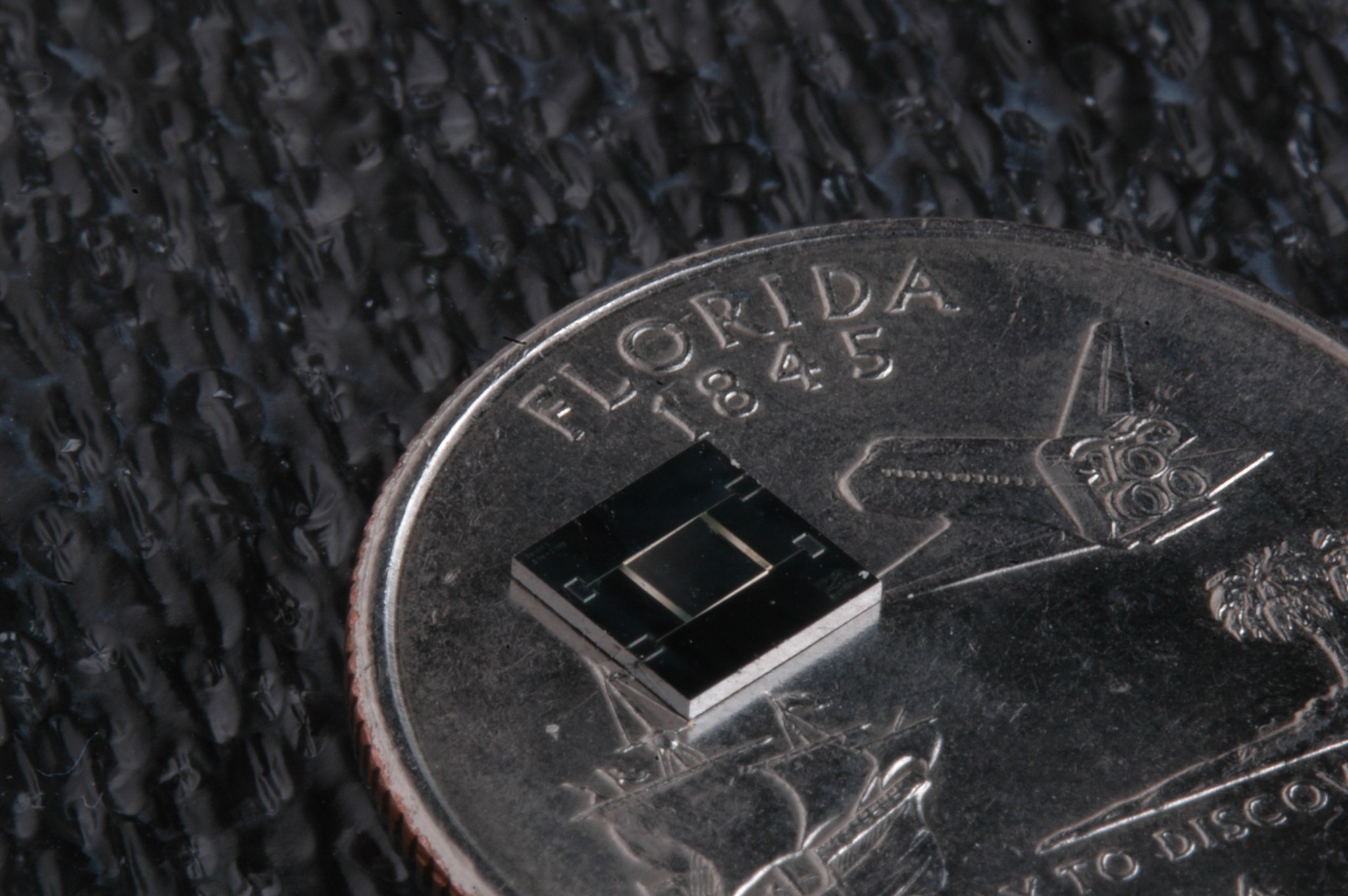 A sensor on top of a quarter to show it's small size.