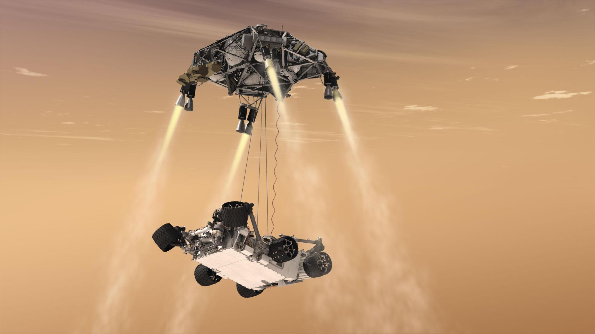 An artist’s concept of the 2012 Mars Curiosity Landing using the skycrane maneuver, with the rover hanging below the hovering spacecraft via three nylon tethers.