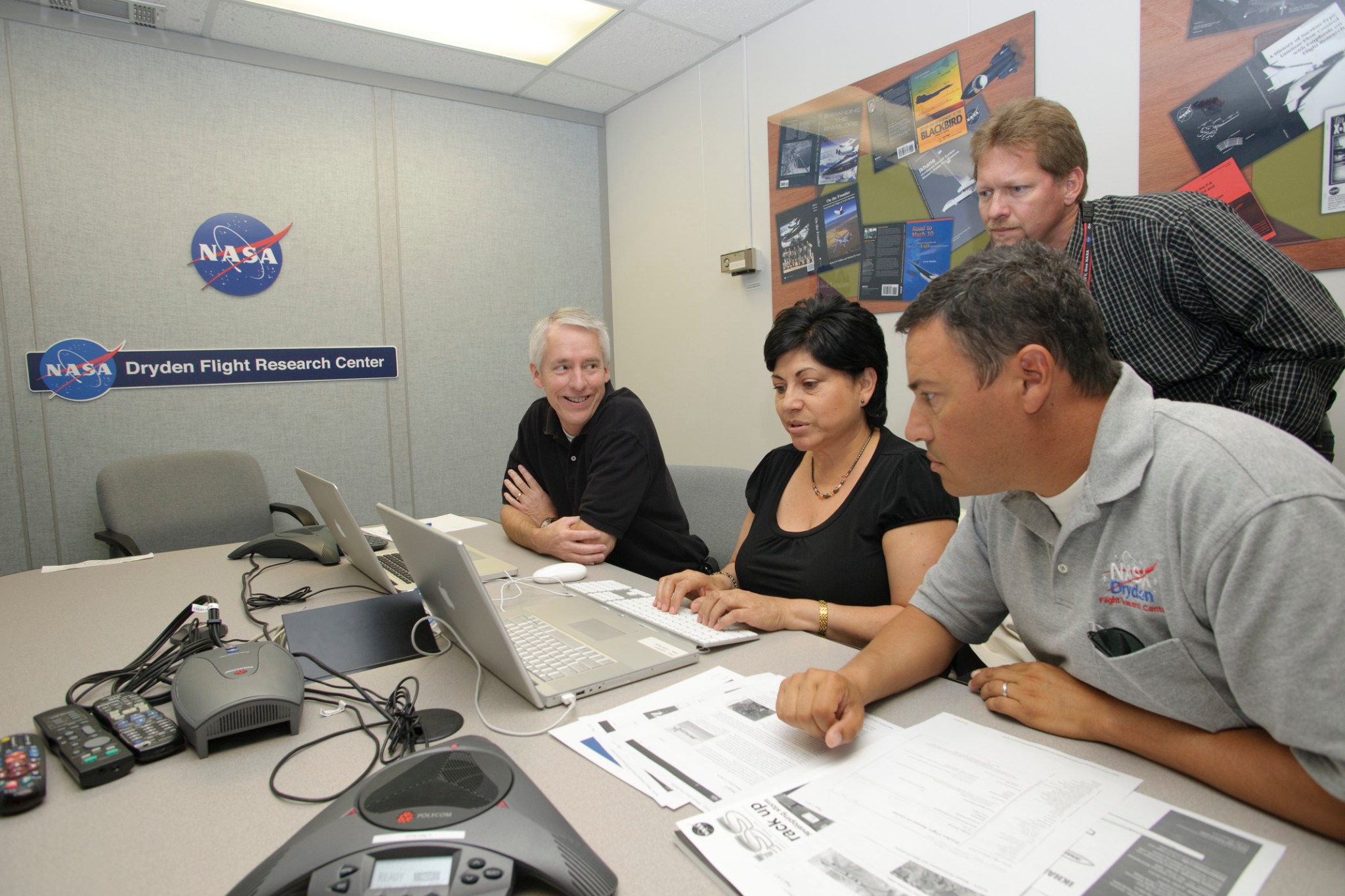 NASA employees and NASA Pilot Posada sitting at a table participating in a webchat.