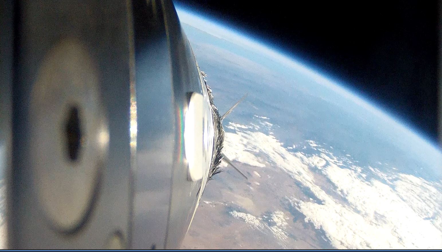An along-the-side view of a sounding rocket in space above Earth