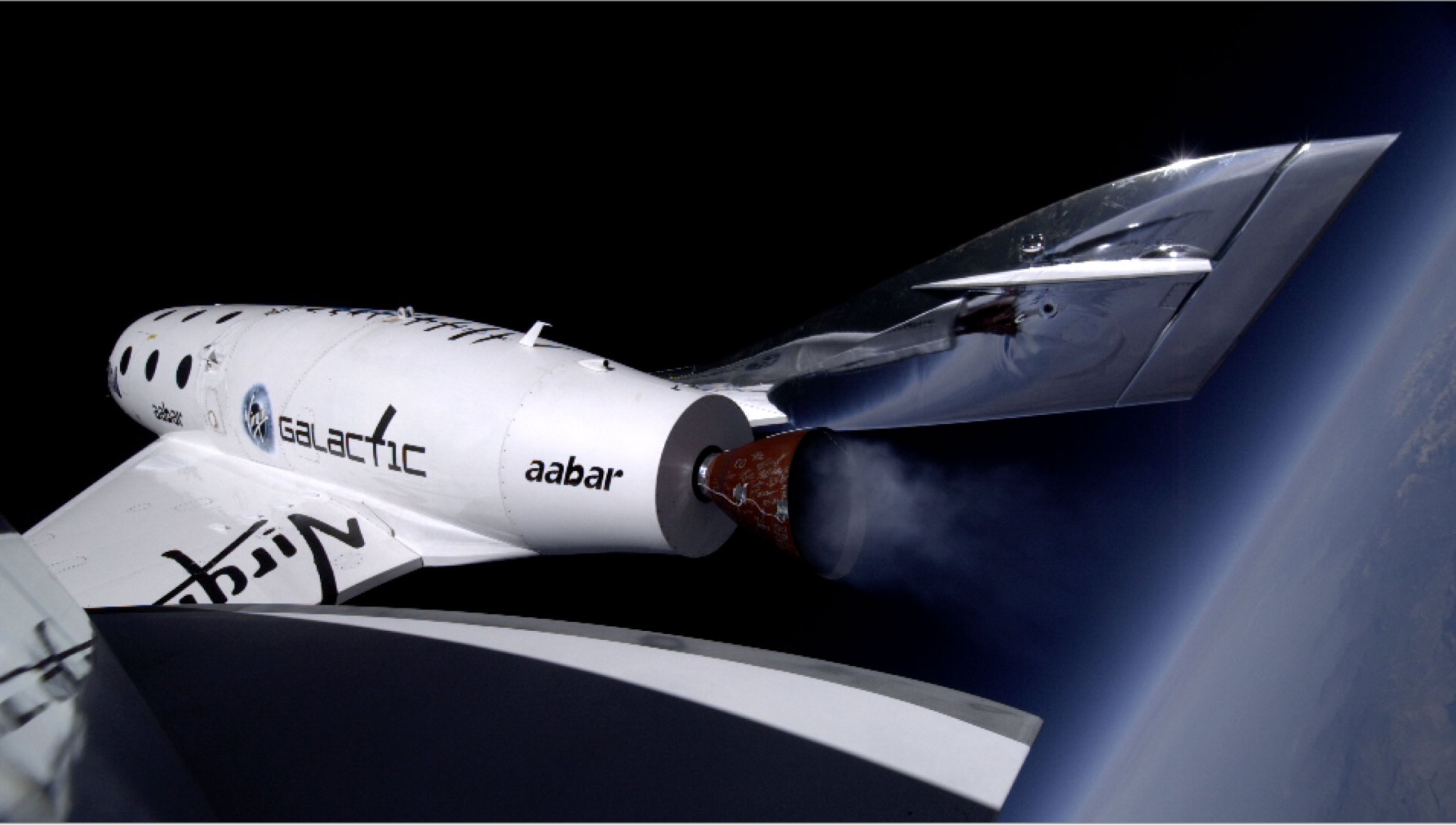 A camera mounted atop the left vertical fin of Virgin Galactic / Scaled Composites SpaceShipTwo captures the vehicle gliding through the upper atmosphere after its rocket engine is shut down during a 2013 test flight. The Earth's horizon can be seen at lower right.