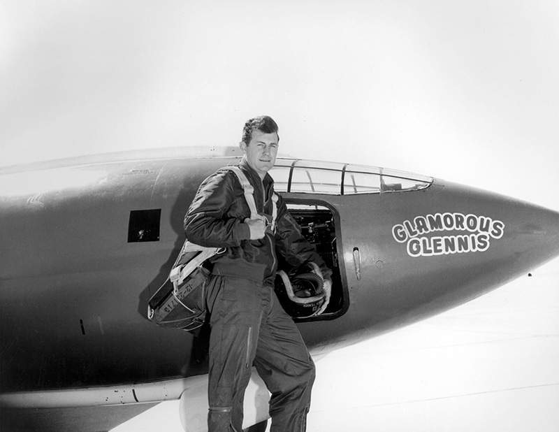 A black and white photo of Chuck Yeager standing next to the Bell X-1.