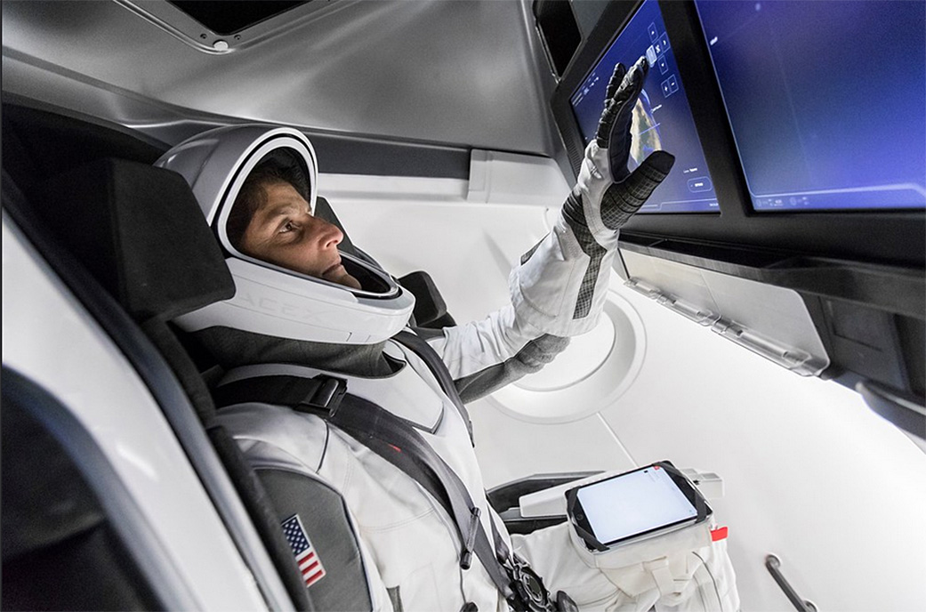 Astronaut Suni Williams, fully suited in SpaceX’s spacesuit, interfaces with the display inside a mock-up of the Crew Dragon
