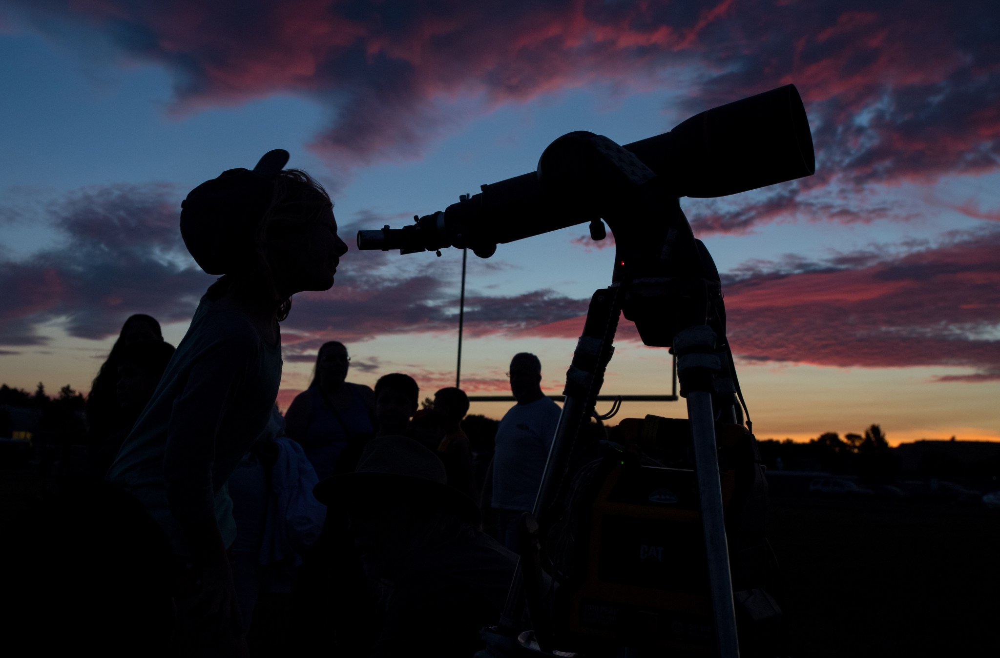 A person looking through a telescope at dusk