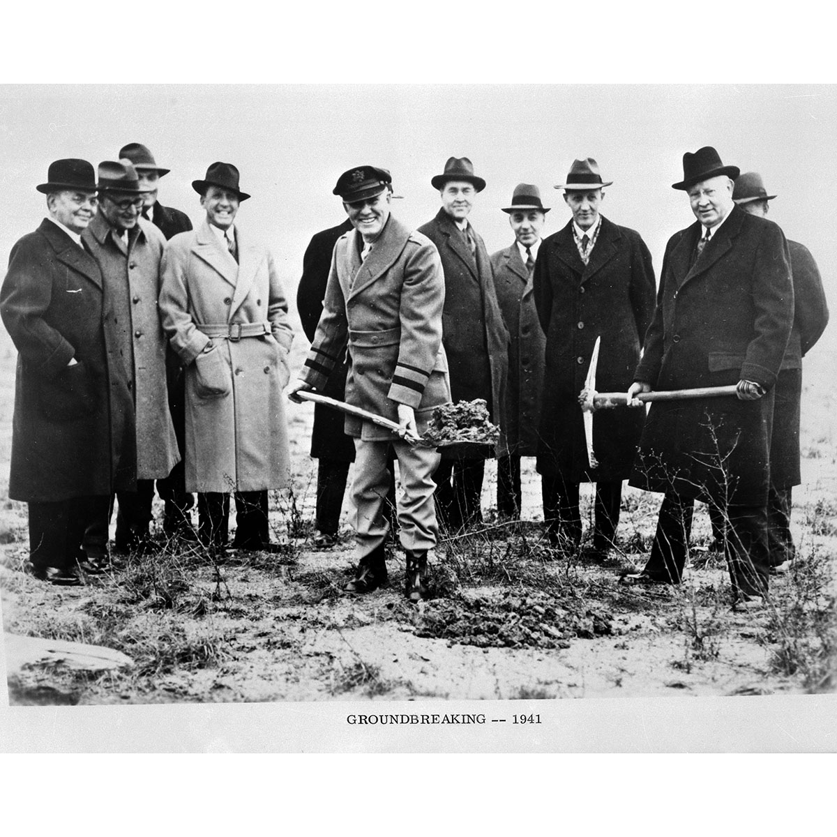 Group of men holding shovels to scoop the first shovel of soil at building groundbreaking.