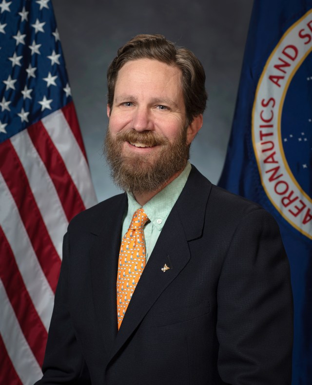 Portrait of Seth Harbaugh with U.S. and NASA flags in background