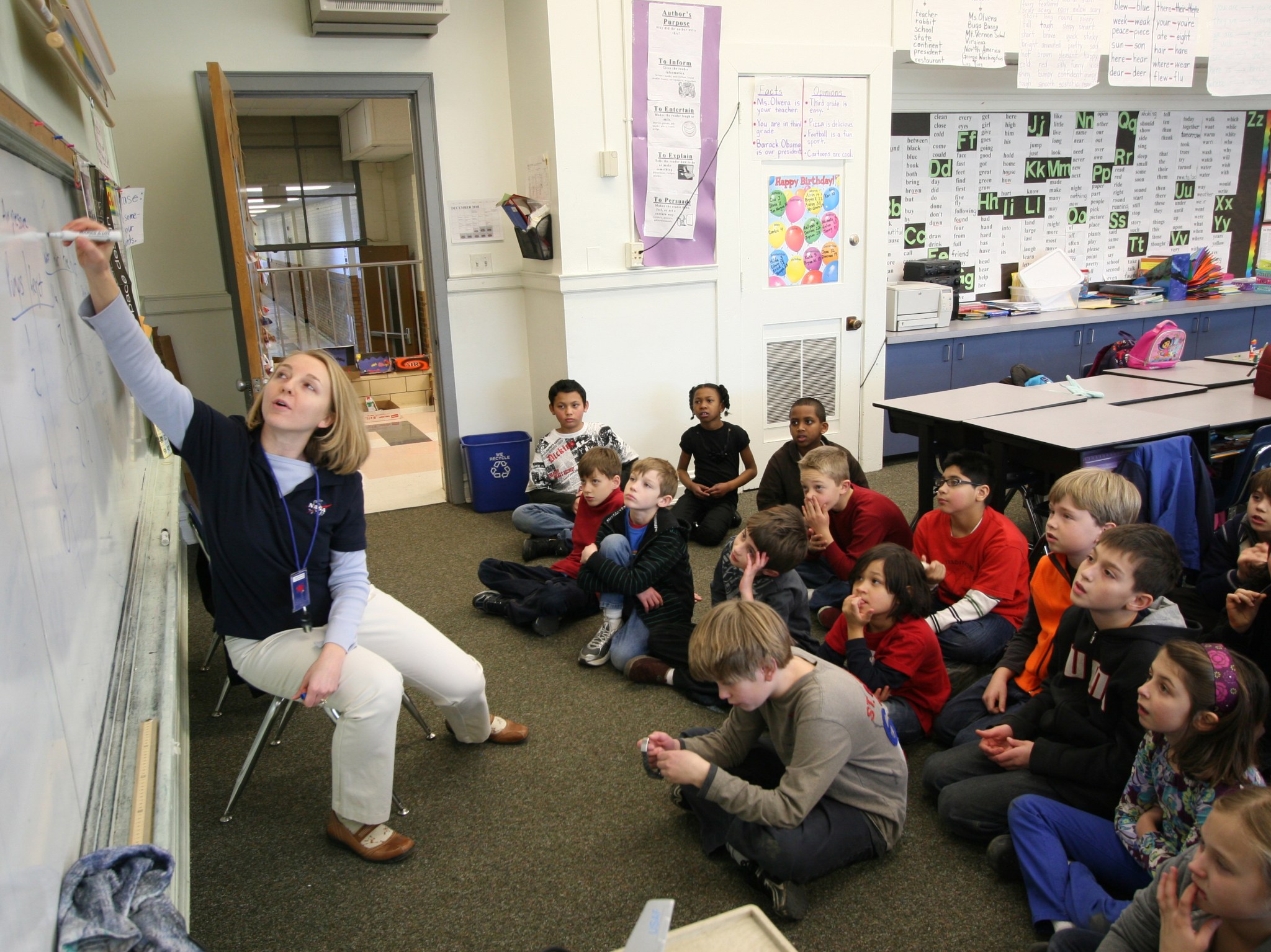 Jenay Leach teaching students while writing on a white board.