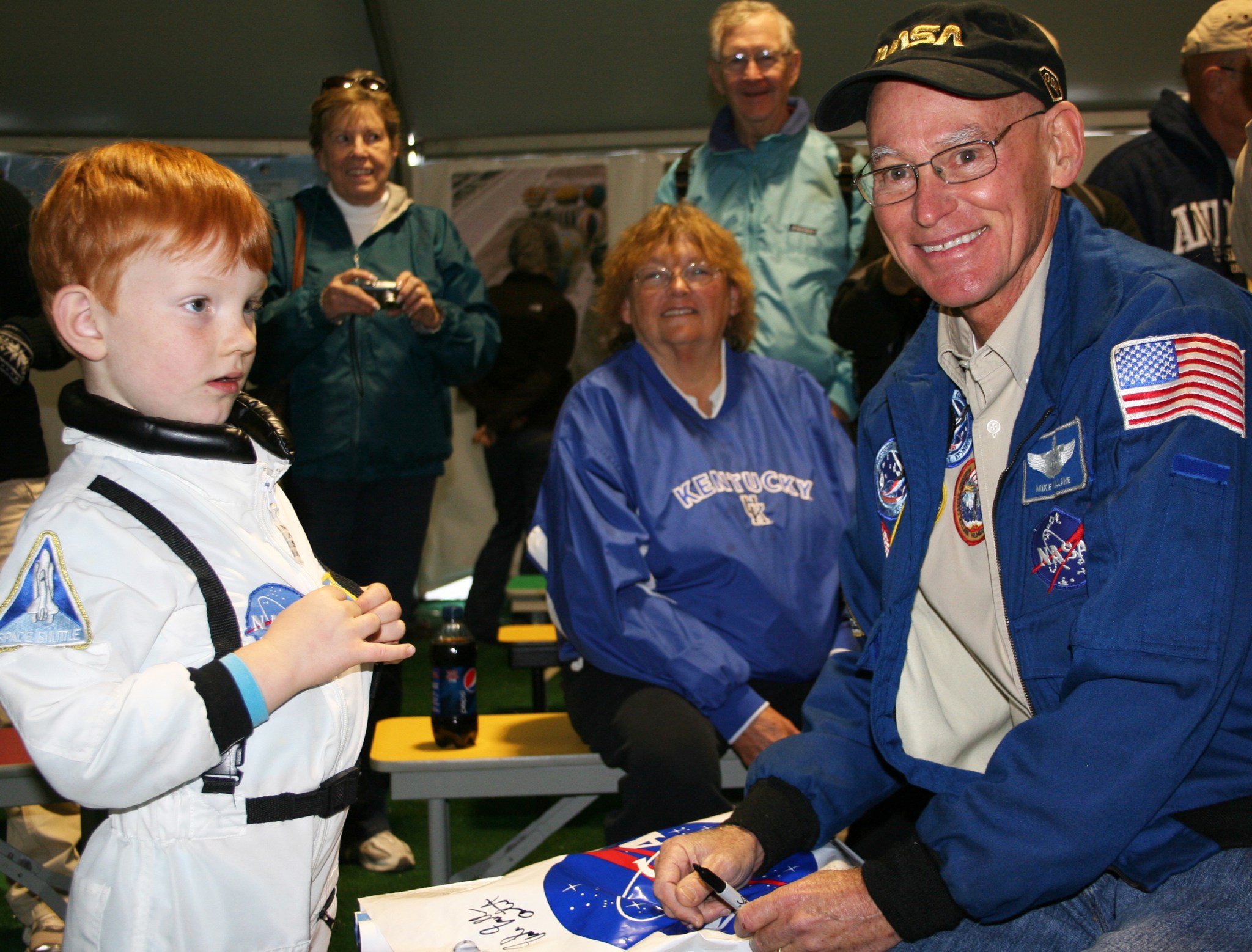 Former NASA astronaut Mike Mullane signs an autograph for aspiring astronaut Seamus Burke.