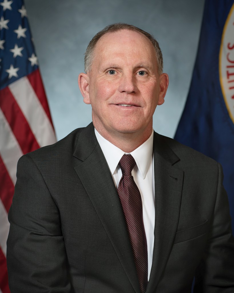 Portrait of Larry Sivic with U.S. and NASA flags in background
