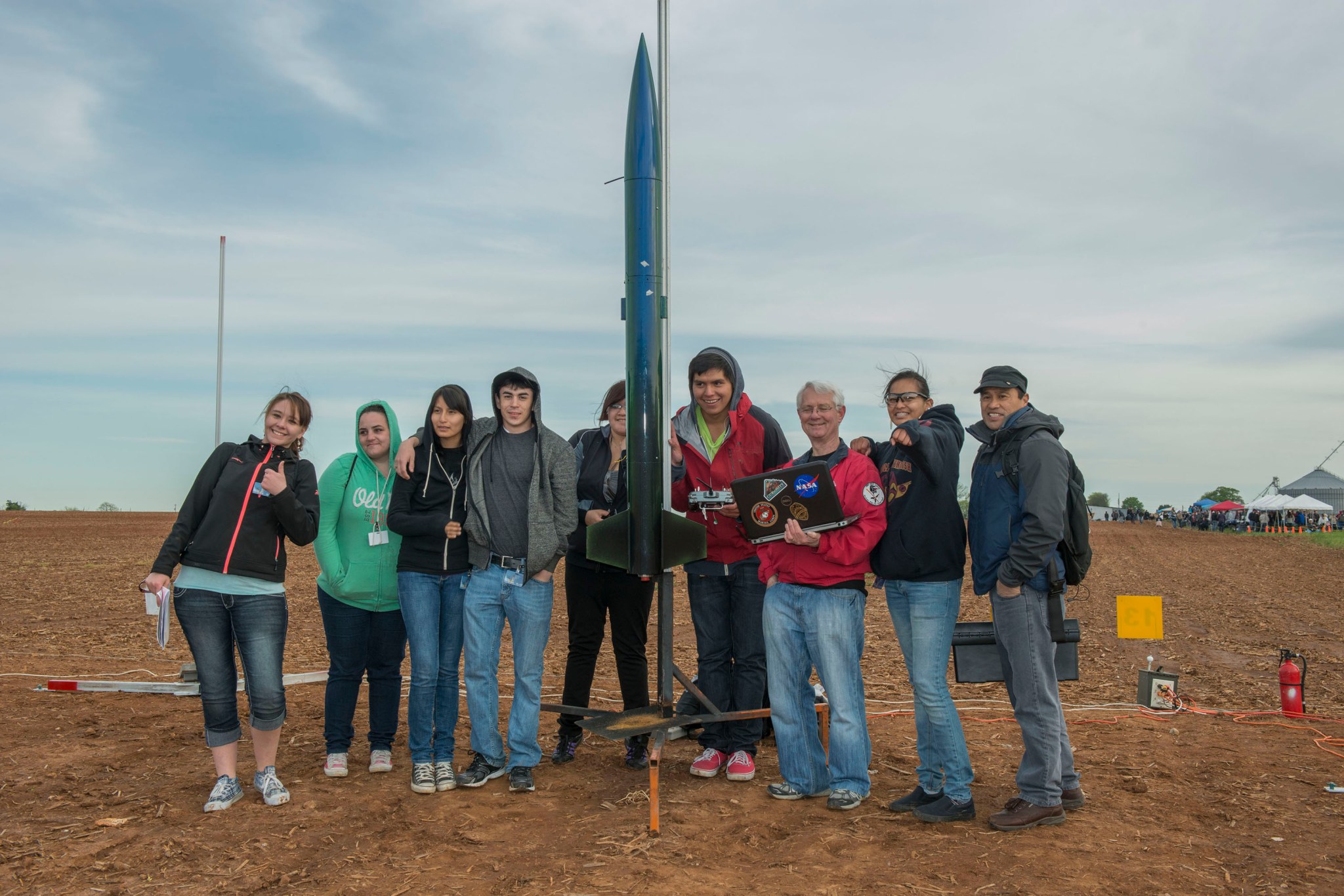 Students and team members from Northwest Indian College stand next to their rocket at a NASA event.