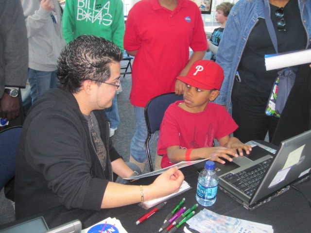 Billy Pacheco helping a student who is sitting at his computer.