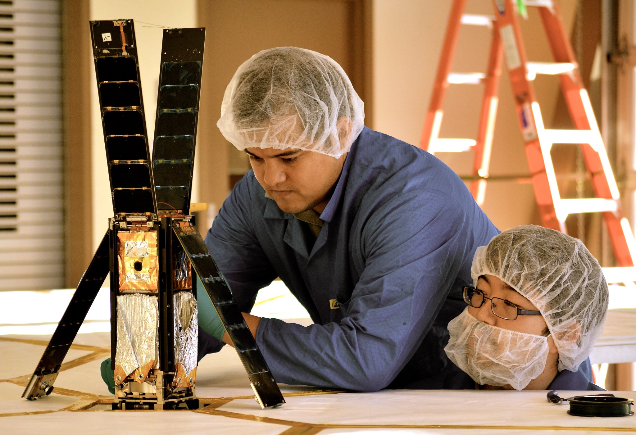LightSail team members Alex Diaz and Riki Munakata prepare the spacecraft for a sail deployment test. 