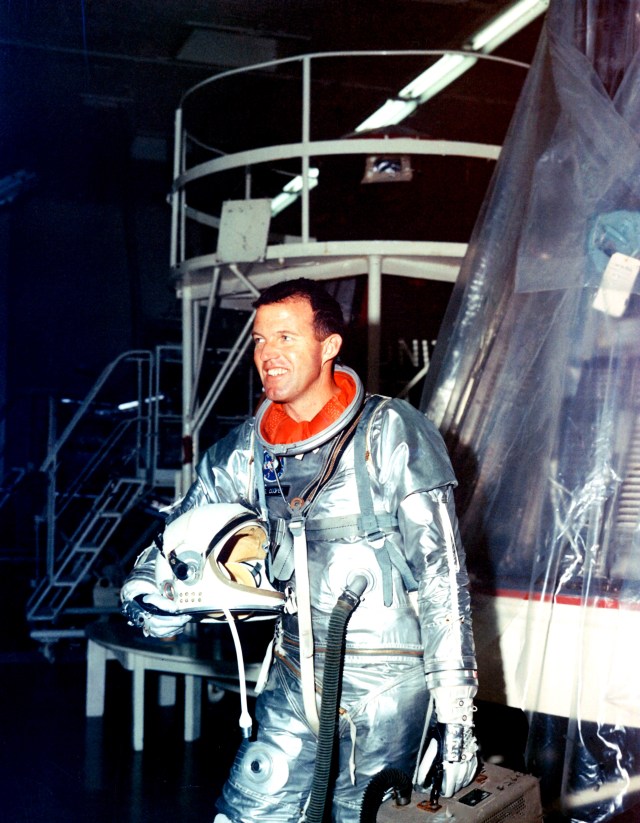 Astronaut Gordon Cooper stands fully suited beside the Faith 7 spacecraft.