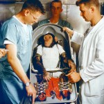 CHIMPANZEE "HAM" sits IN FLIGHT COUCH FOR MR-2 (MERCURY-REDSTONE2) surrounded by his trainers.