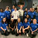 A group of students stand and kneel smiling with Dr. Steven Levin.