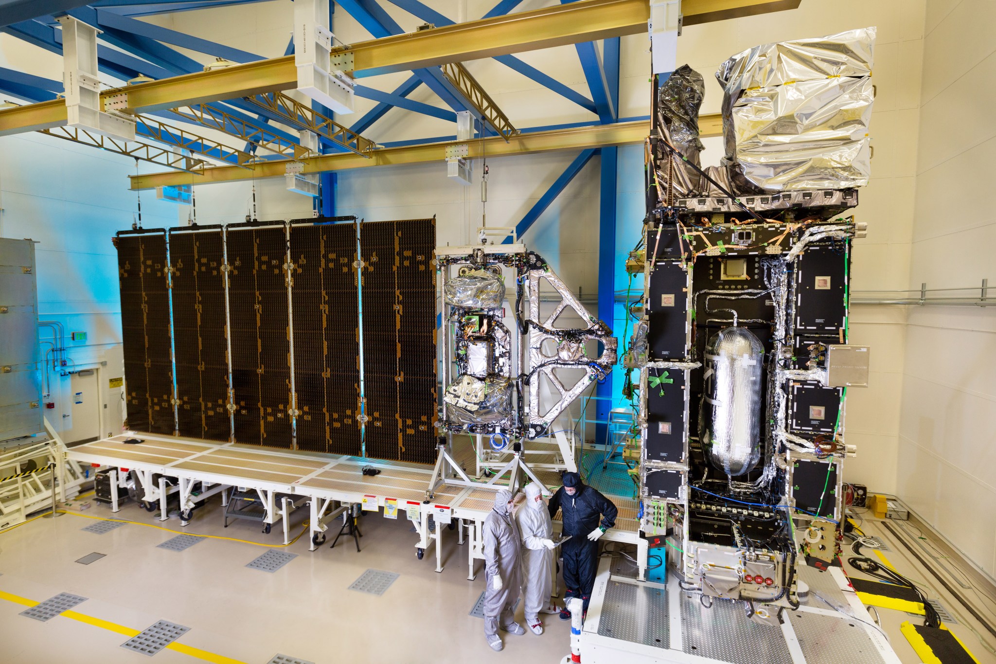 From above, three men stand in a large room with instrumentation