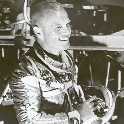 John Glenn smiles while wearing the silver spacesuit worn by Mercury astronauts 