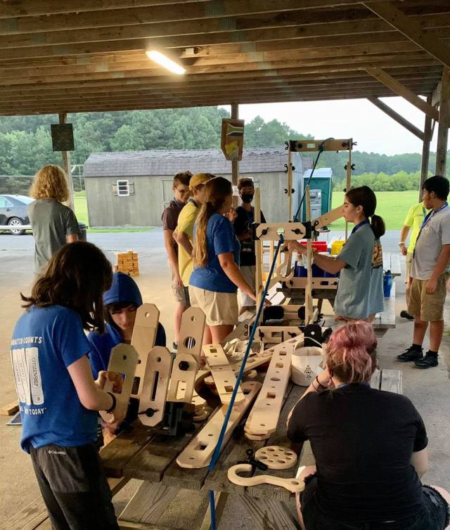 A group of students creating a structure with large wood blocks and planks