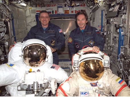 Two astronauts posing with their space suits in the ISS