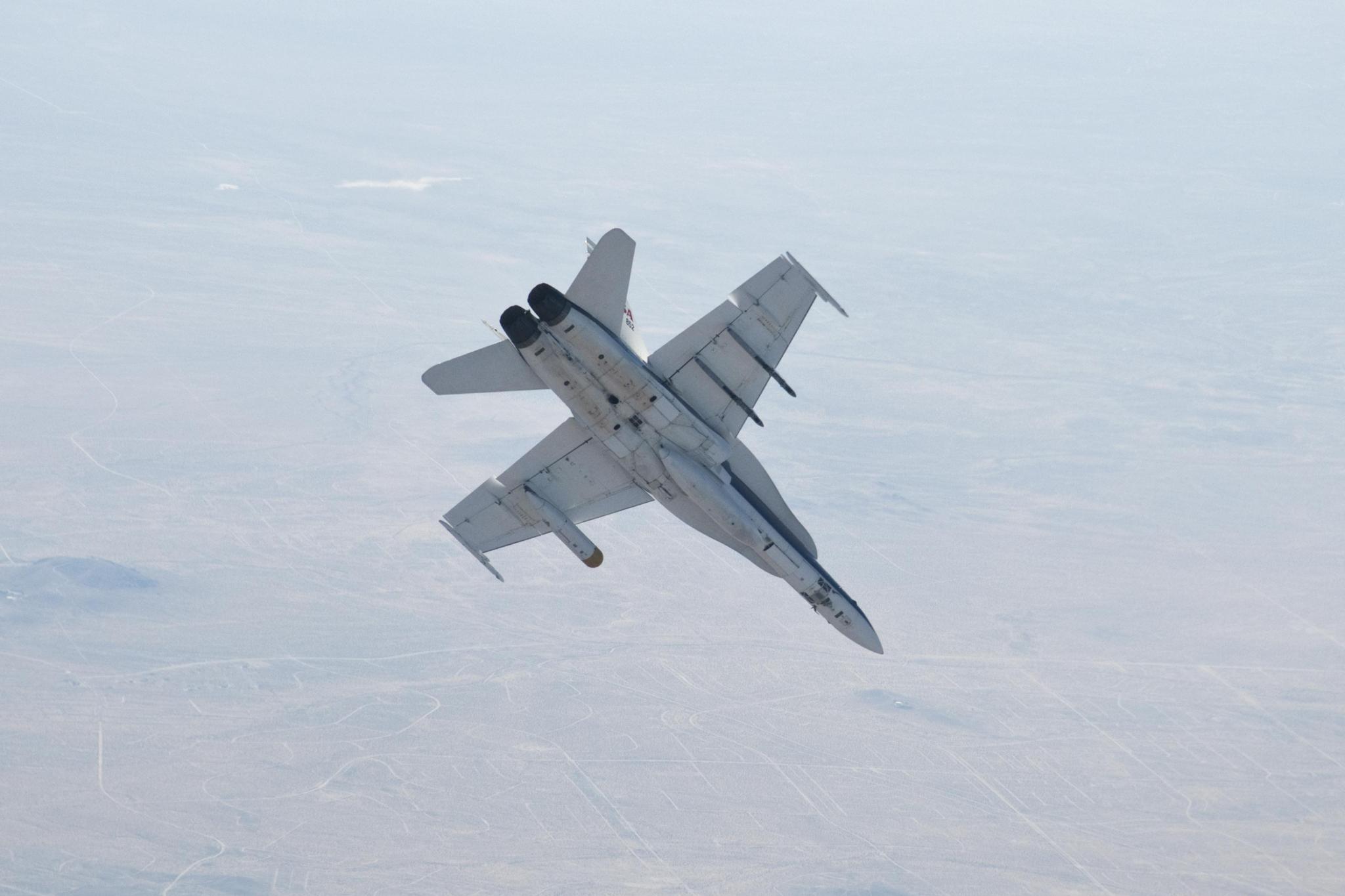The underside of a fighter jet flying above Mojave Desert