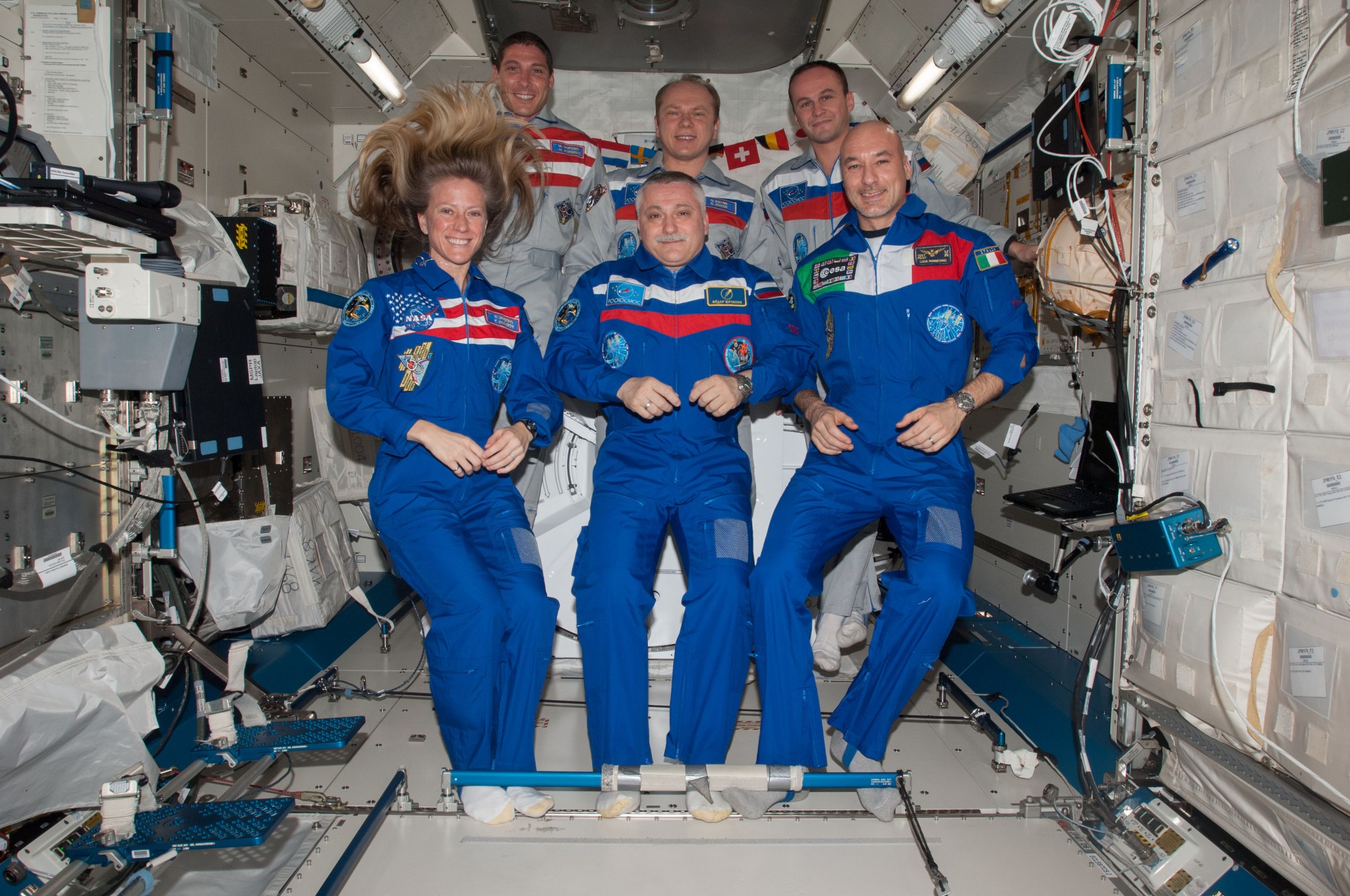Three cosmonauts and three astronauts pose inside the International Space Station