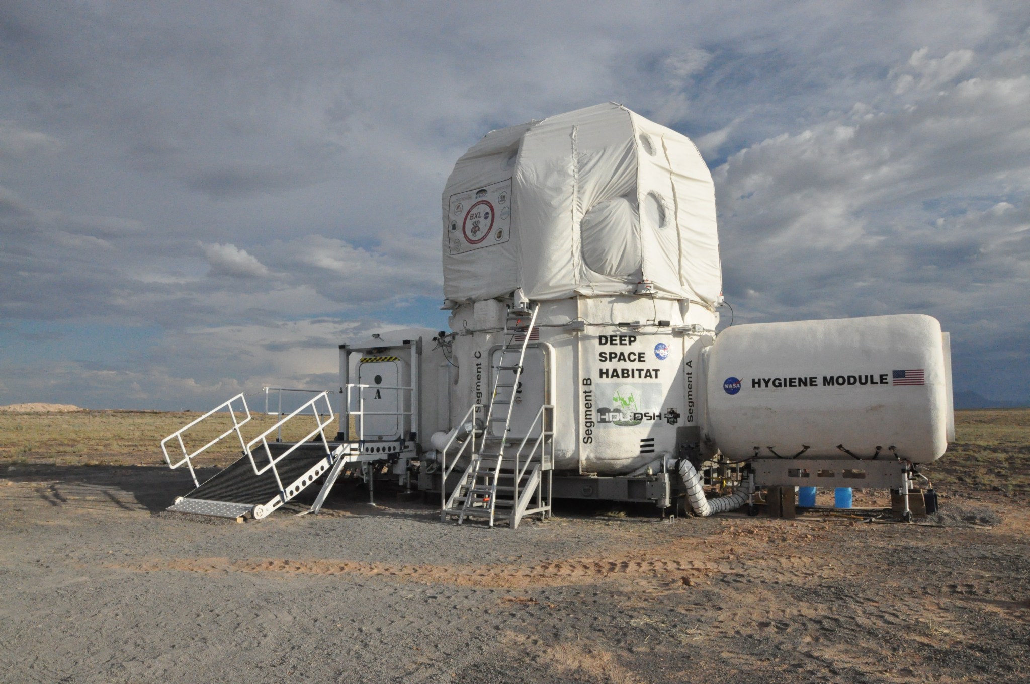 A white building, with the words Deep Space Habitat on its side, sits in the desert