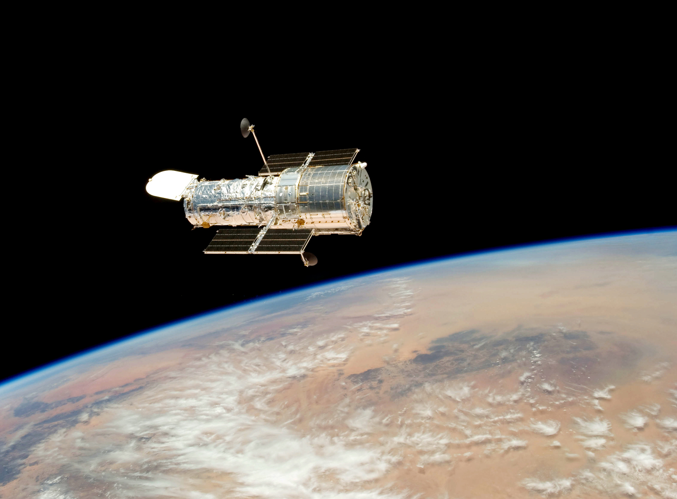 A picture of the Hubble Space Telescope floating over earth.