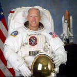 Astronaut Patrick Forrester poses for a picture in a white spacesuit