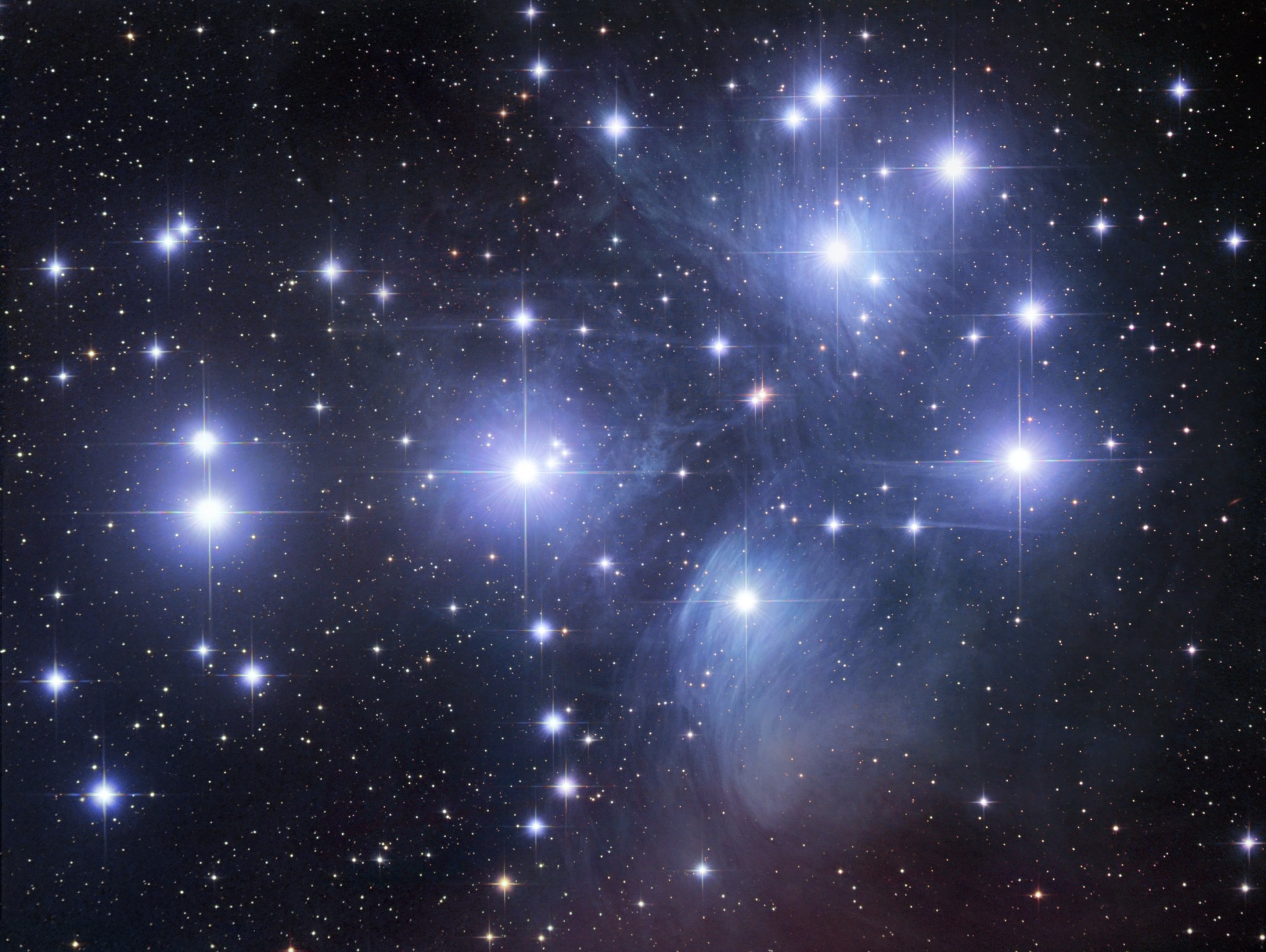 The Pleiades star cluster, shown as a large cluster of lights on a starry background.