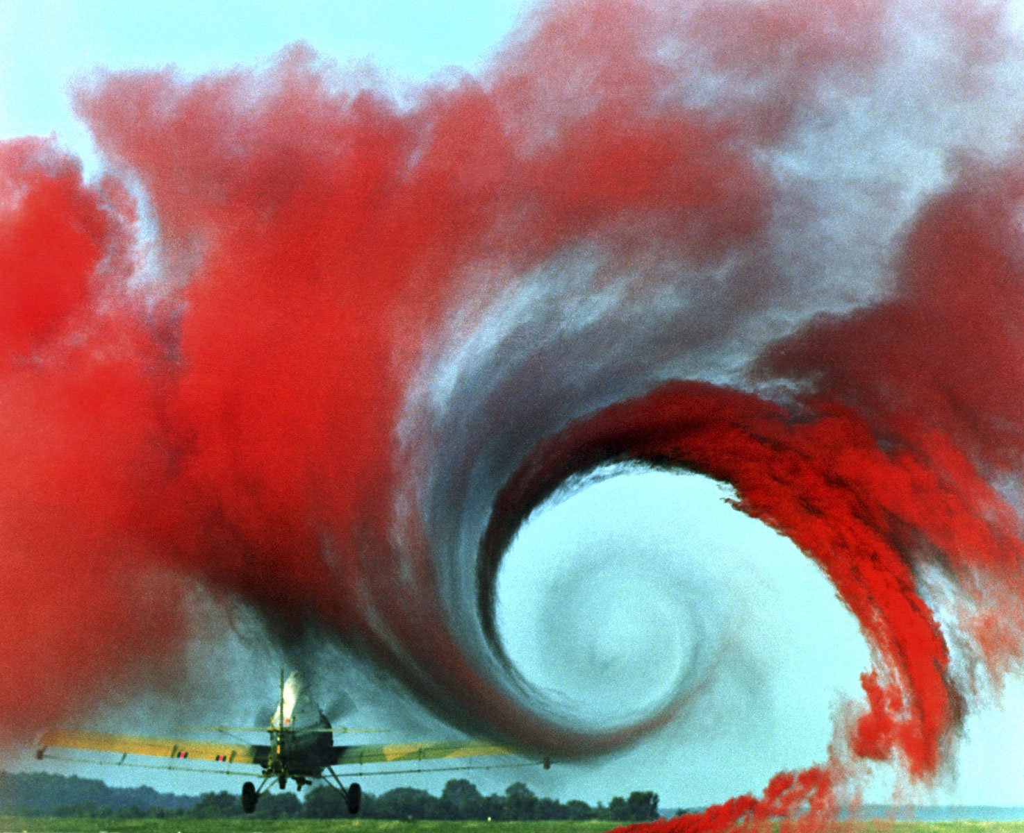 Red smoke on the ground shows the vortex made by the air flowing from the wing of the airplane.
