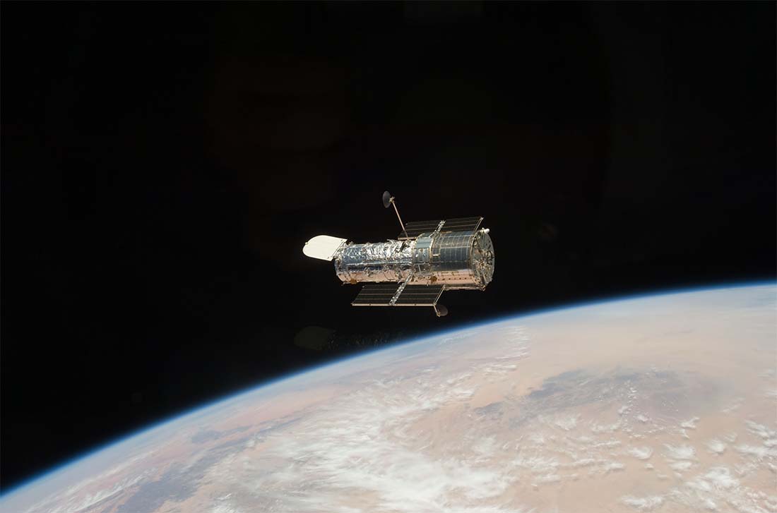 The large silver Hubble Space Telescope orbits above Earth
