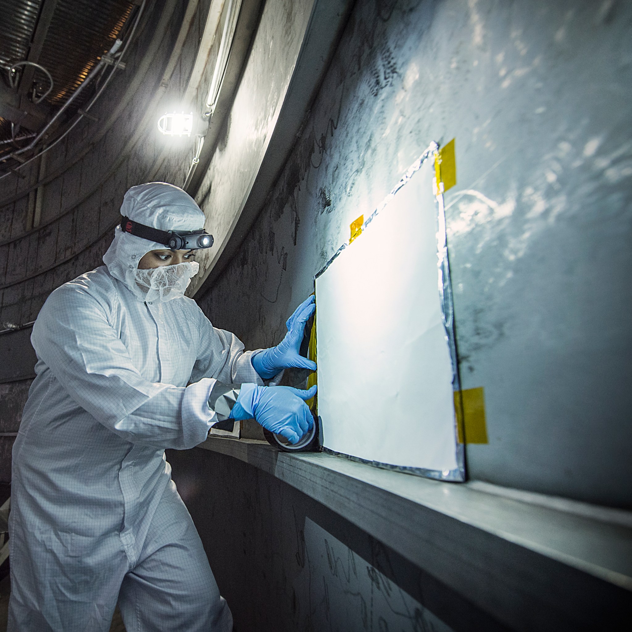 Thermal Coatings Engineer Nithin Abraham places a MAC panel at the very bottom of the Chamber A