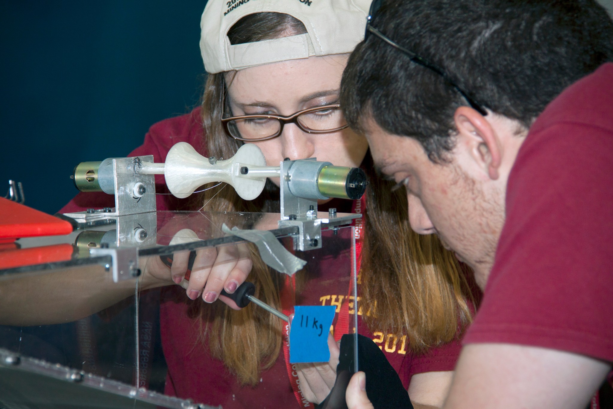 Team members make adjustments to their robot miner before a test run in the mining arena.