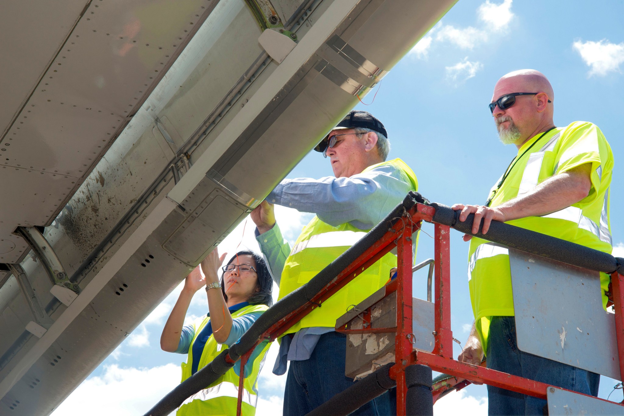 NASA researchers and Boeing technician measure insect residue on experimental wing coating.