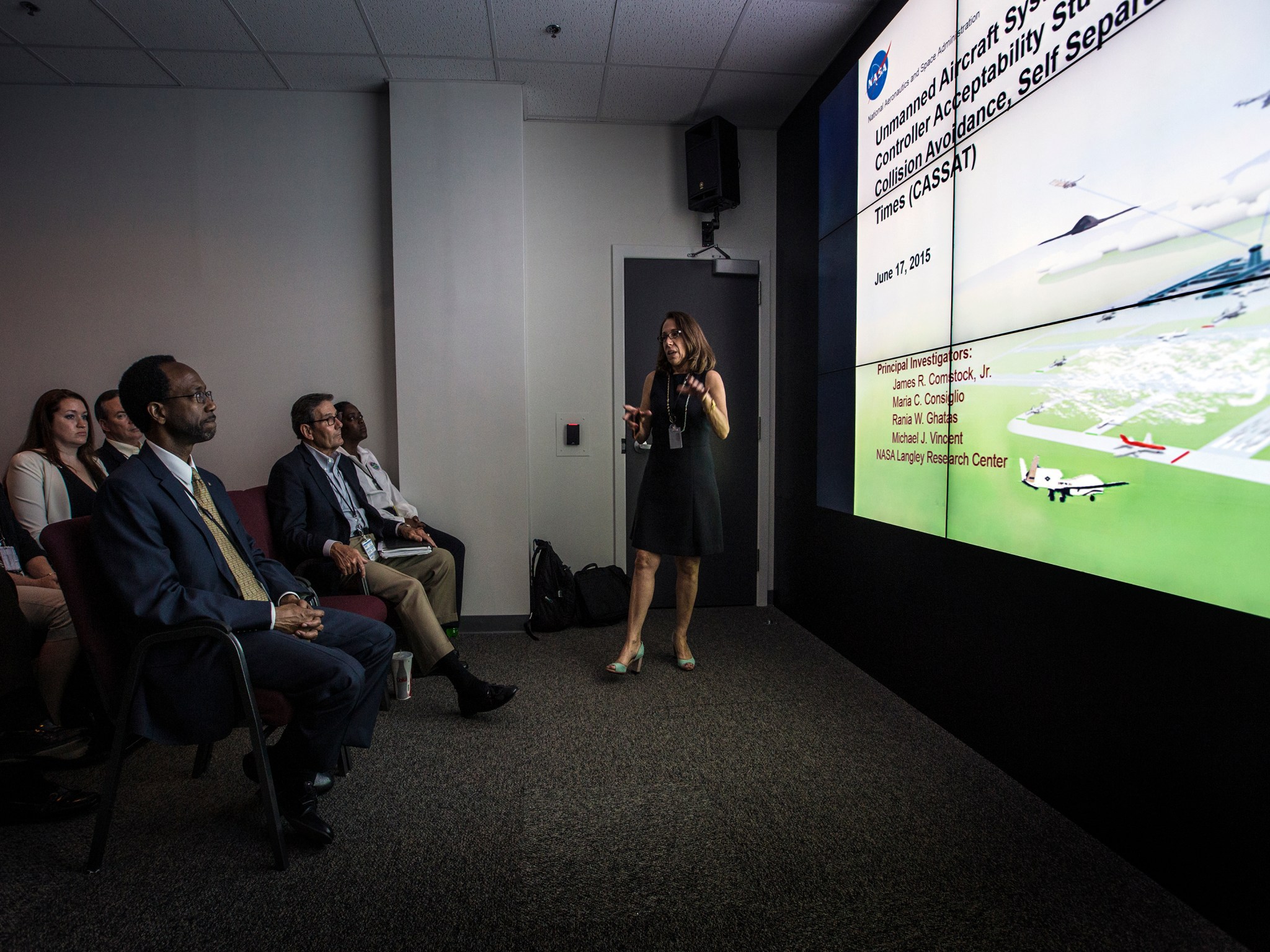 Maria Consiglio, giving a presentation and standing in front of a large monitor display.