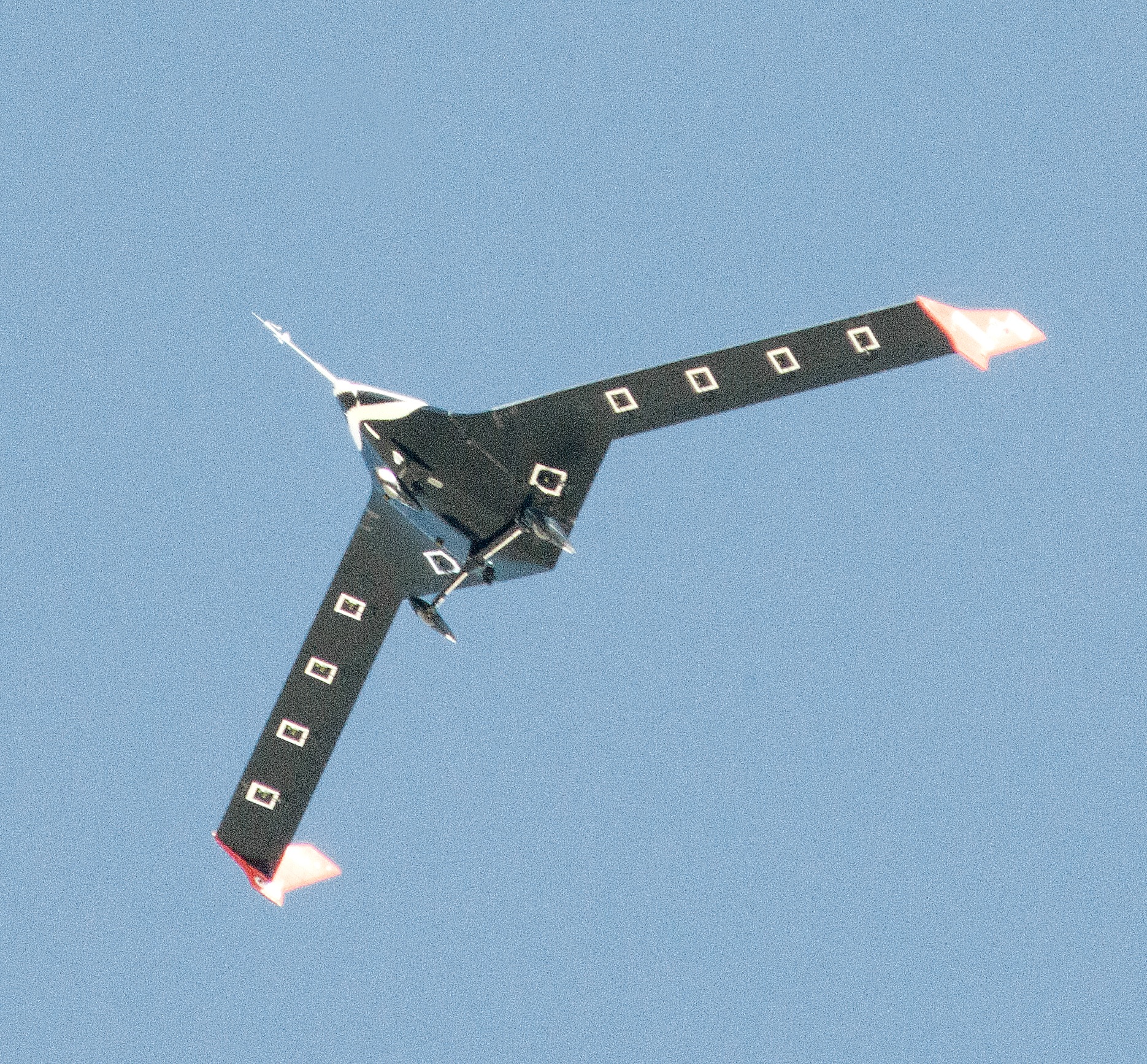 The X-56A is shown overhead in flight. The view is of the belly of the aircraft.