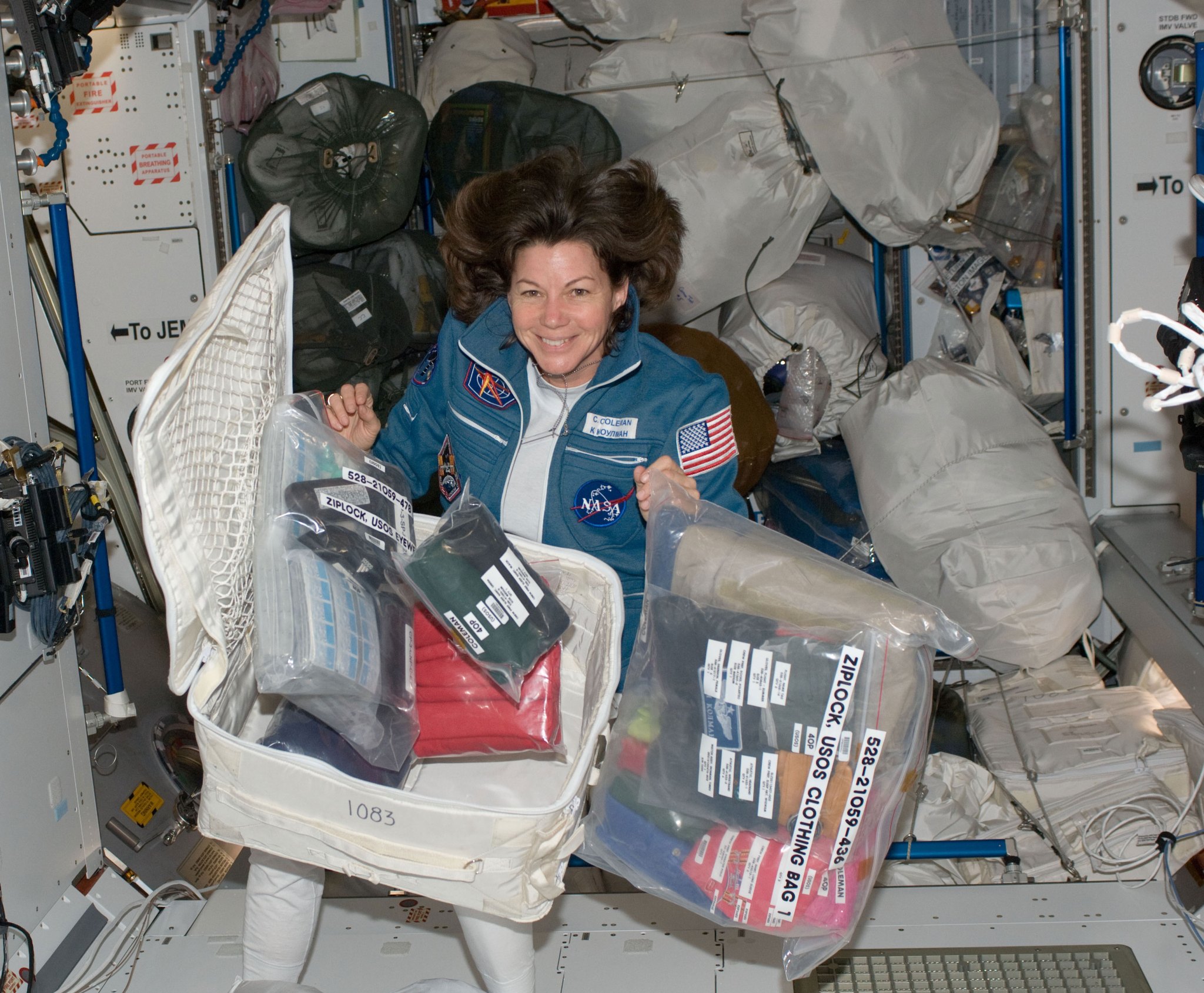 Astronaut Cady Coleman with a stowage container and its contents on the International Space Station