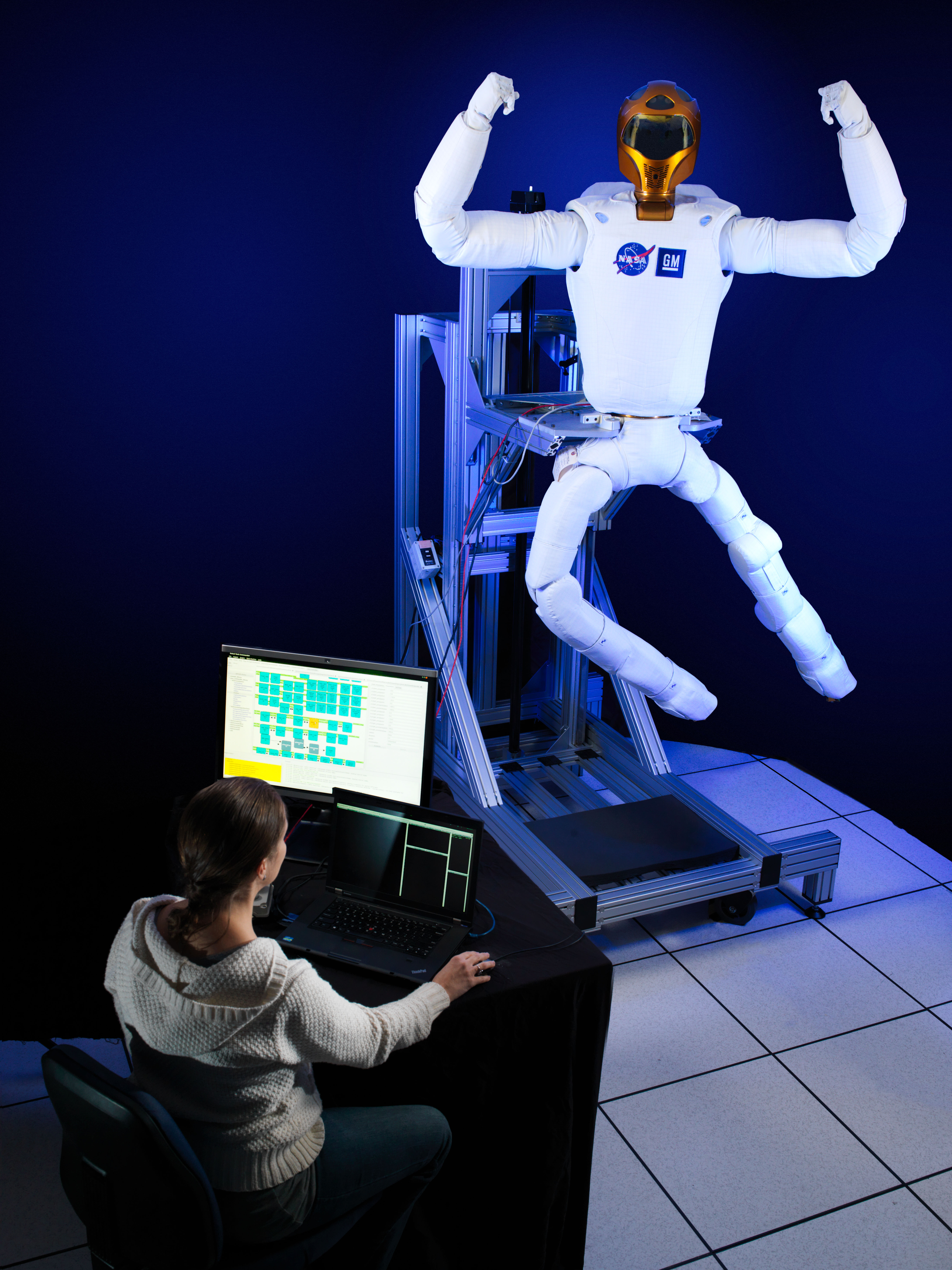 Robonaut 2 (R2) and a woman sitting at a computer nearby
