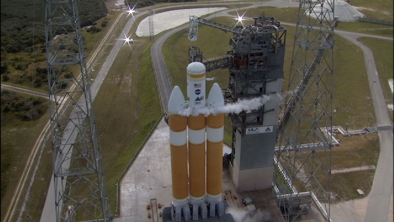 An orange and white rocket sits on the launchpad