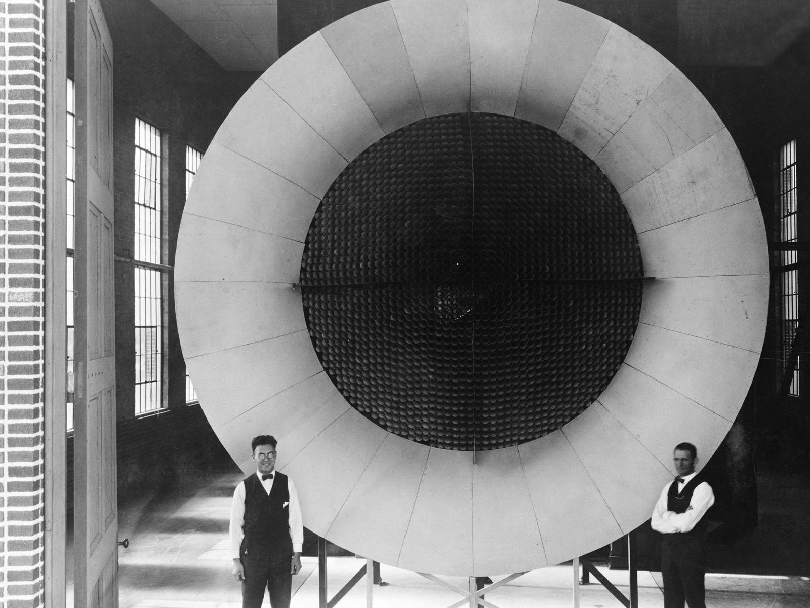 Black and white photo of two men standing in front of the wind tunnel.