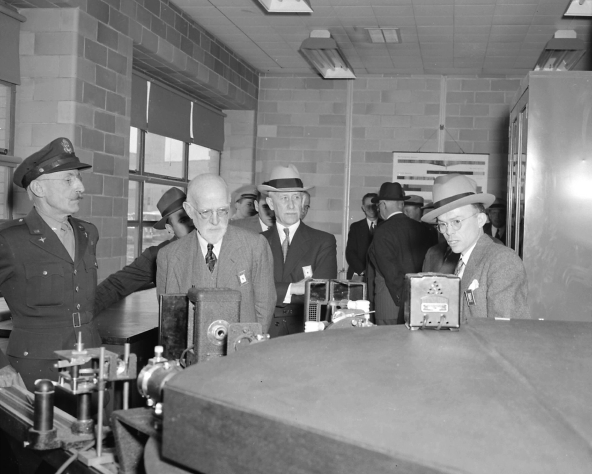 In an image from 1943, Orville Wright inspects some machinery as other men look on.