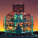 A large aircraft is parked under a large gantry-like steel structure that was used to hoist the shuttle orbiters off the ground.