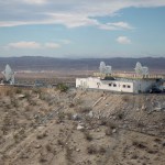 A building on a hill with three radars in the middle of the desert.