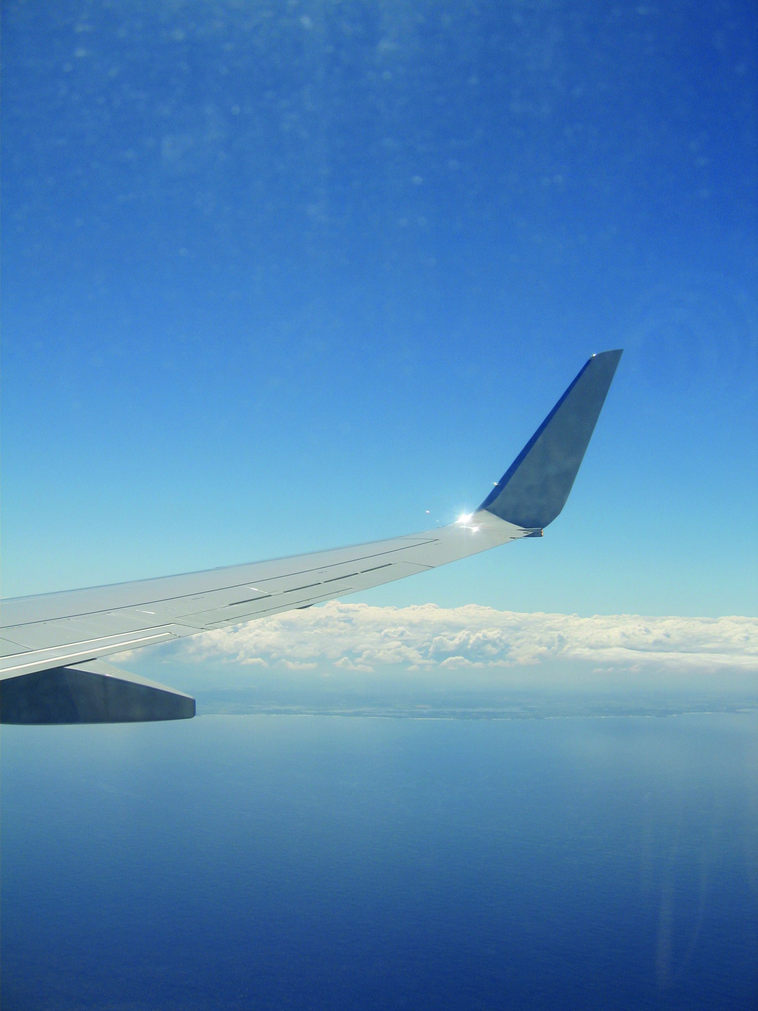 A view from the passenger window of a modern airliner shows a winglet sticking straight up at the tip of the wing.