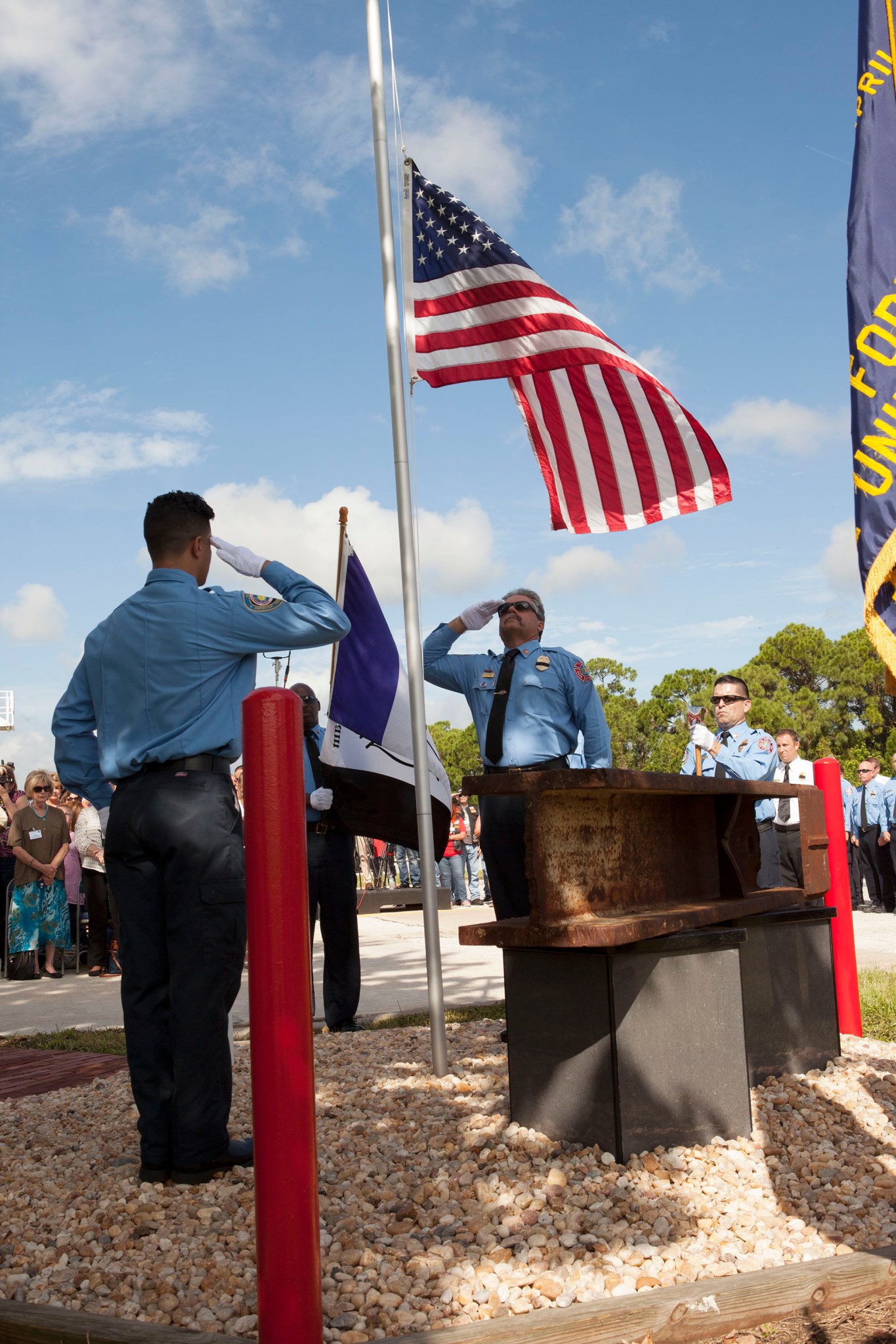 Firefighters place the American flag at half-staff as the beam is unveiled