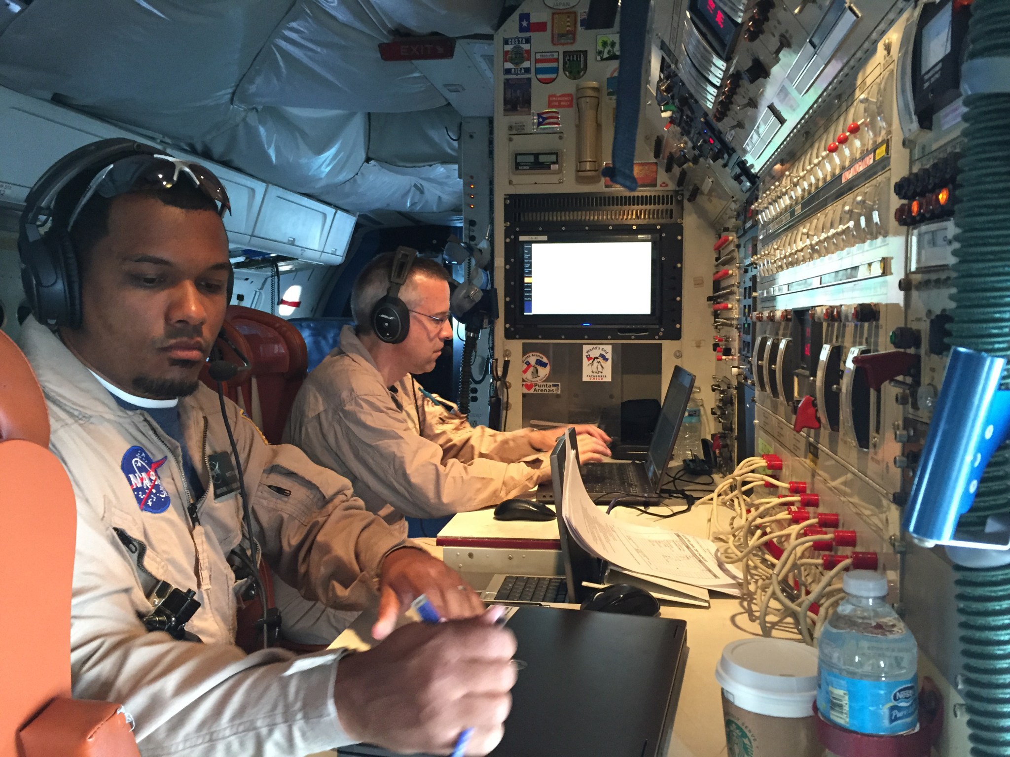 Two men inside the DC-8 aircraft at the operations console.